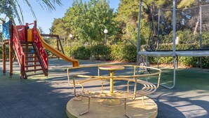 A playground with a seesaw, a merry-go-round, and a slide.
