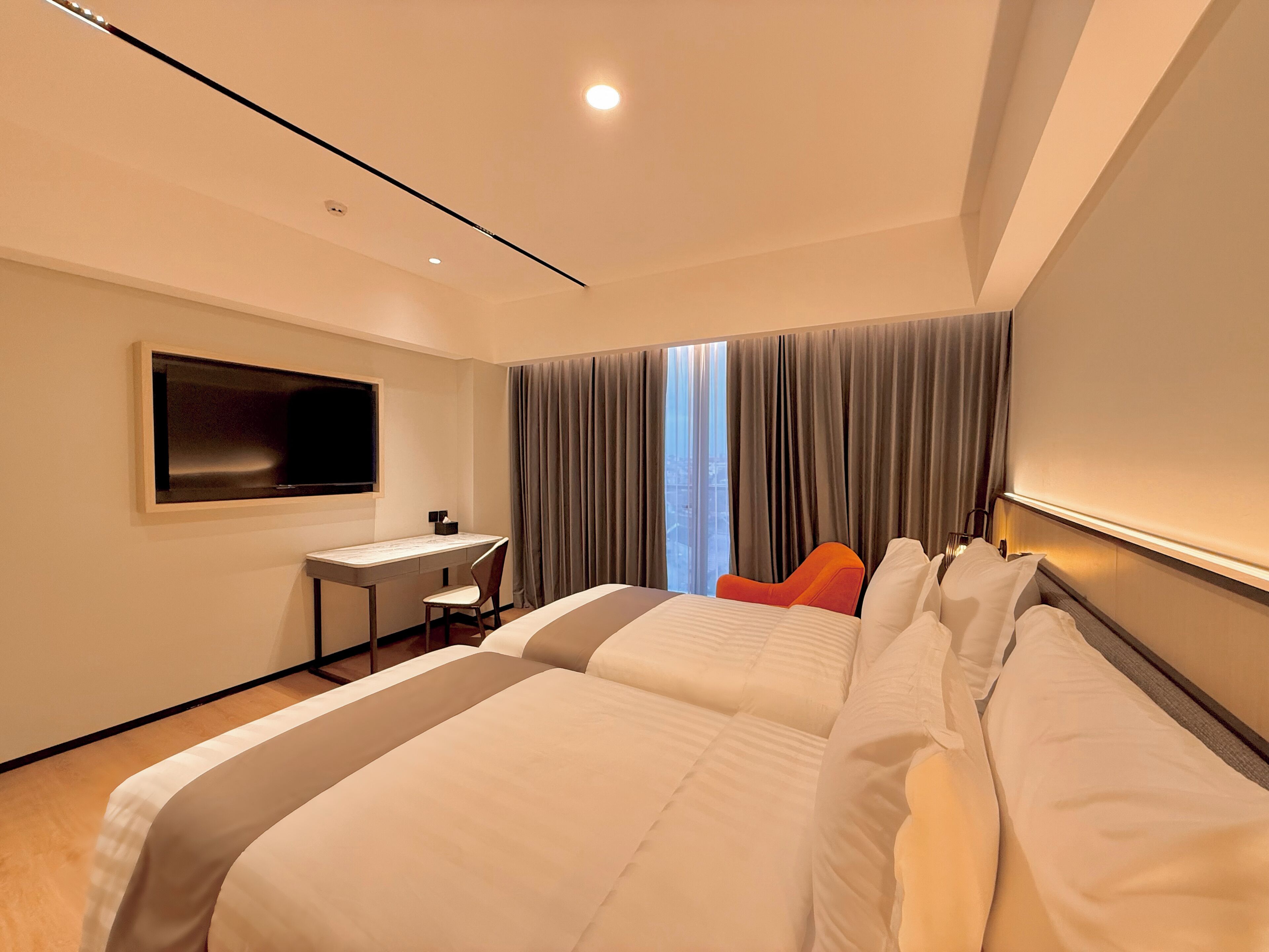Een moderne hotelkamer met een groot bed, een bureau, een flatscreen-tv en uitzicht op de stad.