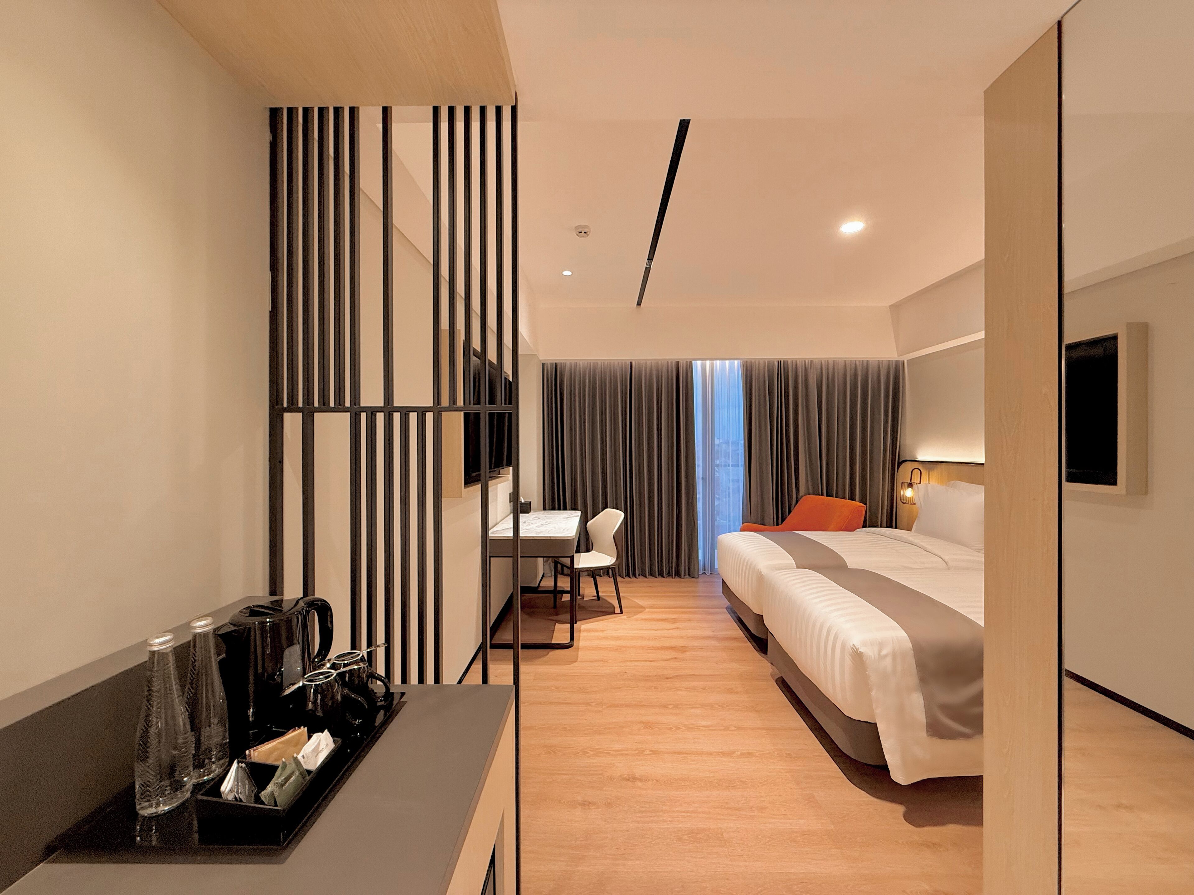A modern hotel room with a bed, a desk, and a TV.