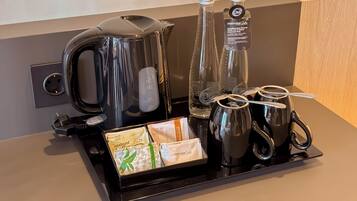 Un coin café équipé d’une machine à café, de deux bouteilles d’eau, d’une bouilloire et de deux tasses.