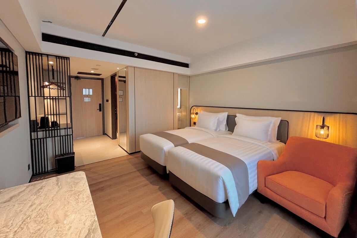 A modern hotel room with a large bed, a desk, and a chair.