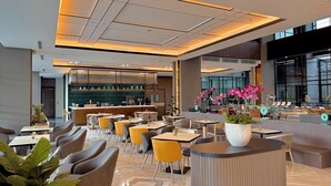 Ein modernes Restaurant mit Barbereich, Sitzgelegenheiten in Gelb und Grau sowie großen Fenstern.
