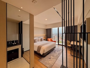Quarto de hotel moderno com uma cama grande, uma escrivaninha e vista para a cidade.