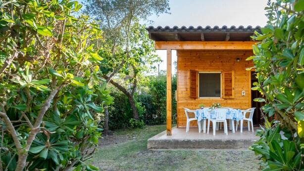 Una cabana de fusta amb un porxo cobert, una taula i caires, i una finestra.
