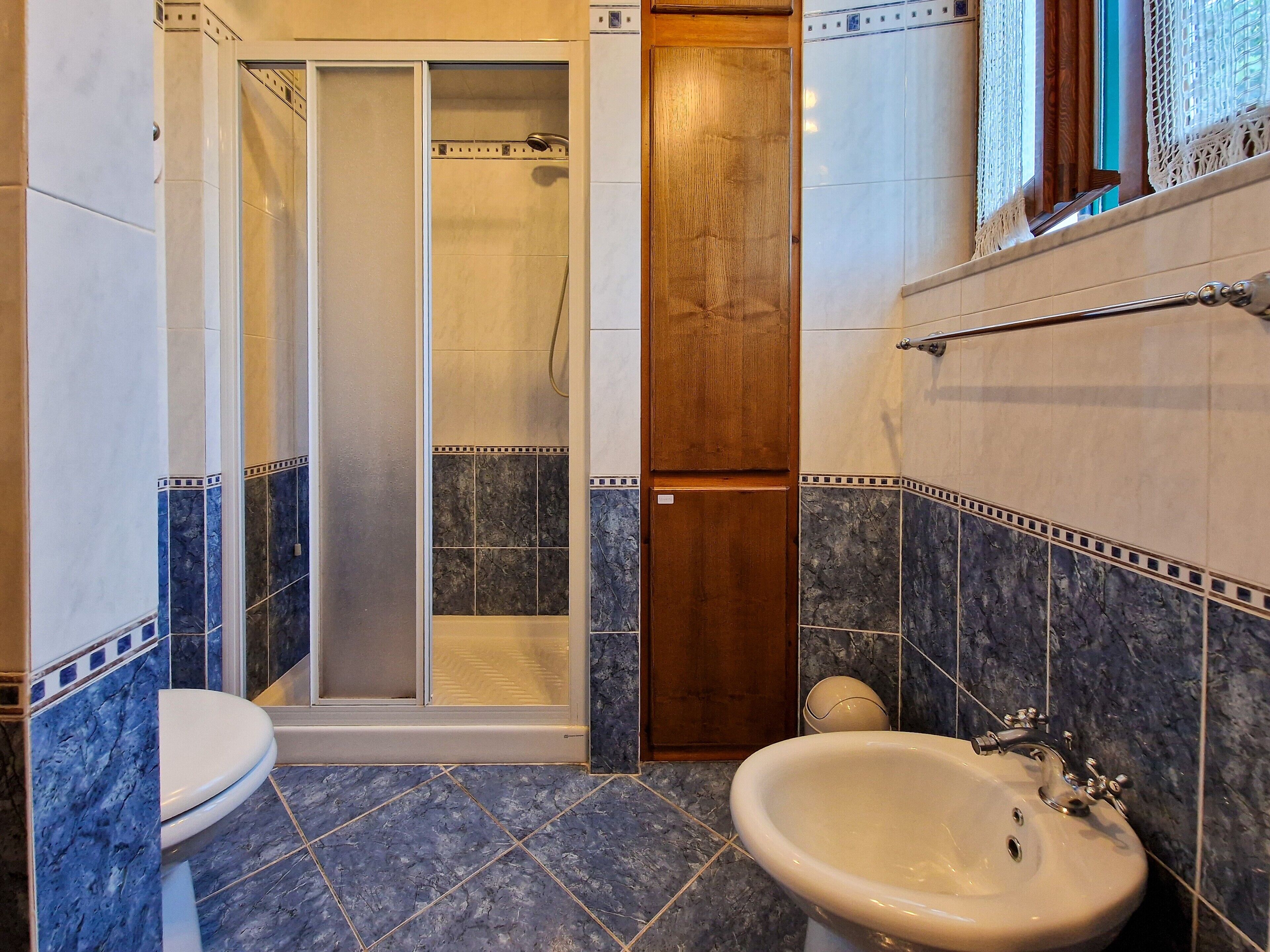Un baño con inodoro, bidé y cabina de ducha.