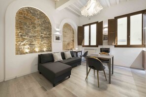 A modern living room with a sectional sofa, a dining table, and a kitchen area.