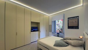 A bedroom with a bed, a TV on a cabinet, a window with a view, and a framed picture on the wall. - Villa Borghese Home & Terrace (Roma)