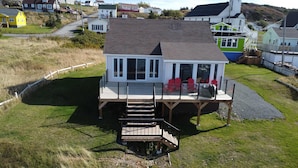 A house with a deck, a staircase, and a view of the surrounding area. - Whales & Trails Vacation Home (Twillingate)