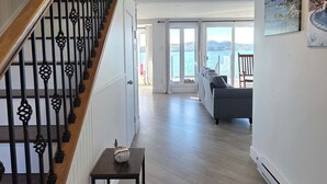 A spacious living area with a wooden staircase, a small table, and a sofa. - Whales & Trails Vacation Home (Twillingate)