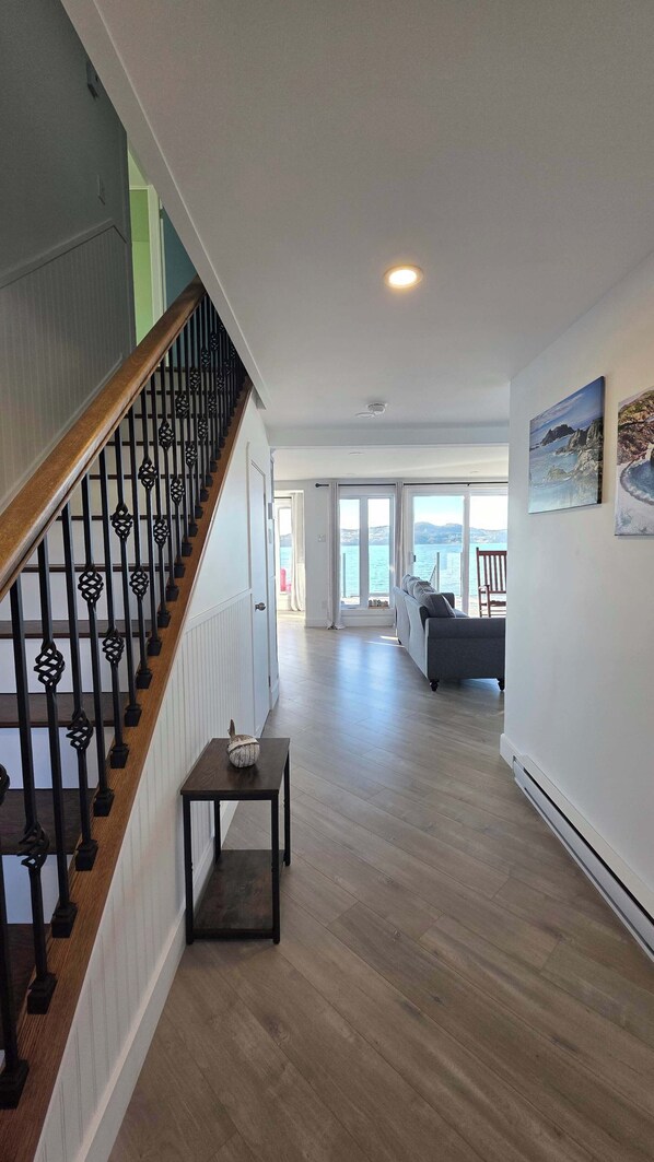 Un espacio habitable amplio con una escalera de madera, una mesita y un sofá.