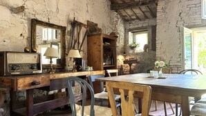 A rustic room with a wooden table, chairs, a radio, a lamp, and a mirror.