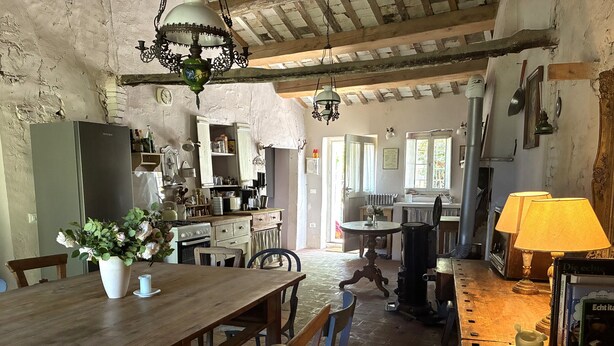 A rustic kitchen with wooden furniture, a dining table with chairs, and a chandelier.