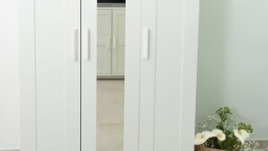 Ein weißer Kleiderschrank mit zwei Türen und einem Spiegel.
