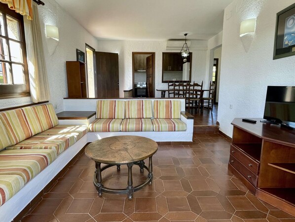 A living room with a sofa, a round coffee table, and a TV stand. - 3 Bedroom Holiday Home Near the Beach (Torroella de Montgrí)