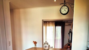 A small kitchen with two bar stools, a clock, and a window with curtains.