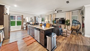 A modern kitchen with a central island, a dining area with a sofa, and a living room with a TV and seating. - 4 King Beds - 2 Game Rooms - Sleeps 24, By DT & UGA (Athens)