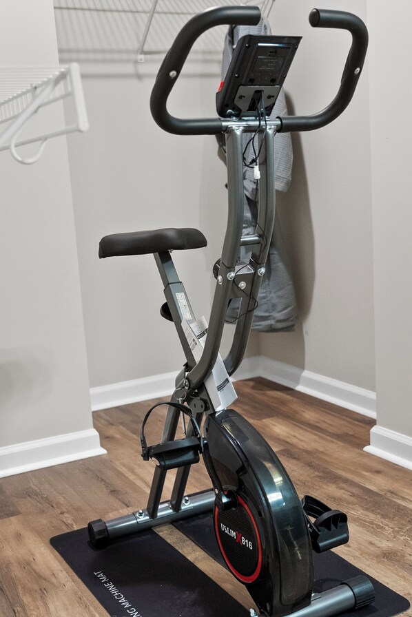 A stationary bike in a room with wooden flooring and white walls.