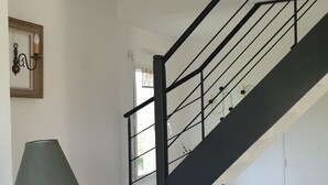 A staircase with a black railing and a woven light fixture above it. - Vacation home -6 to 8 people (Cléder)