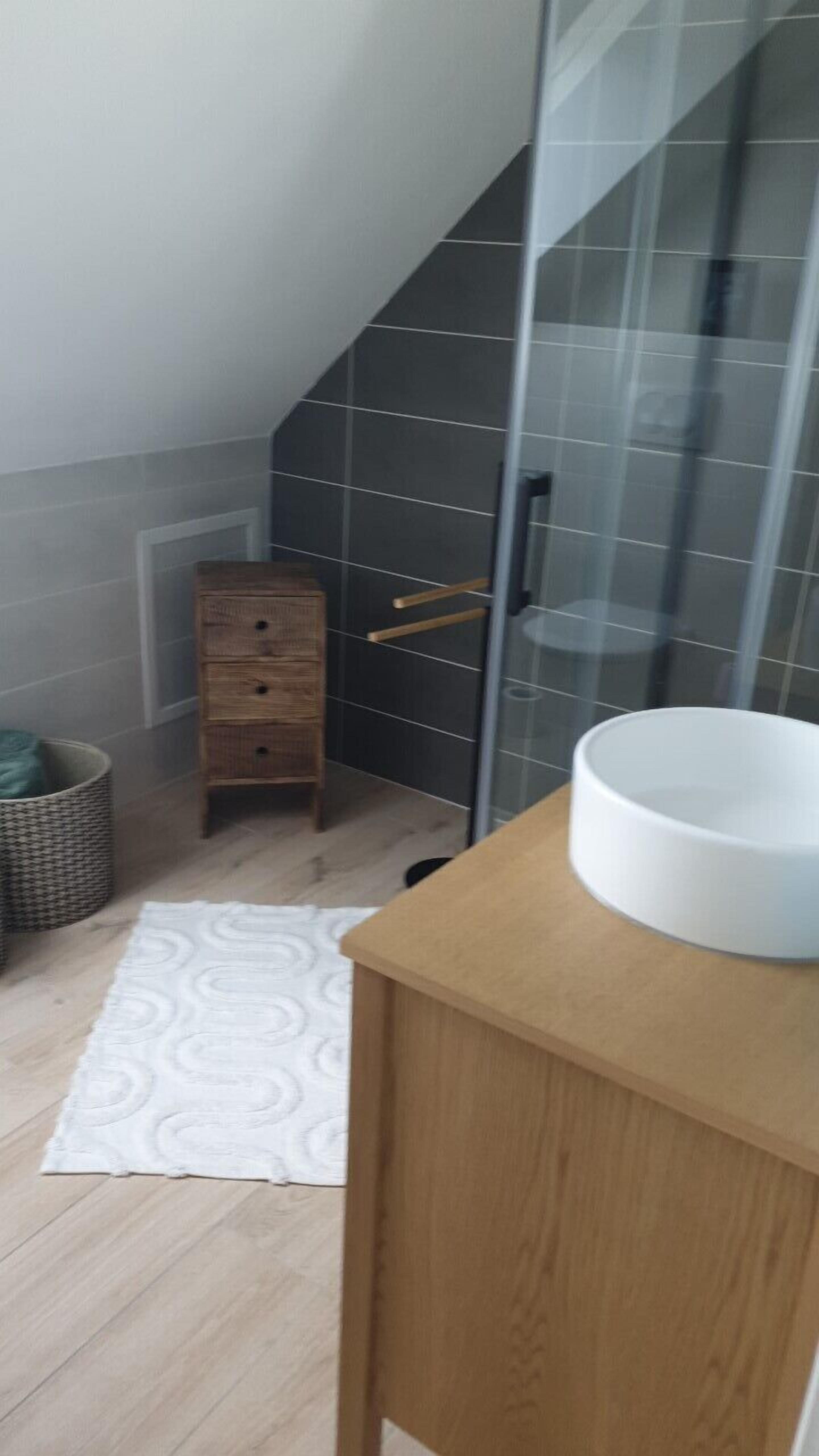 Une salle de bain avec un meuble en bois, un lavabo blanc et un porte-serviettes.