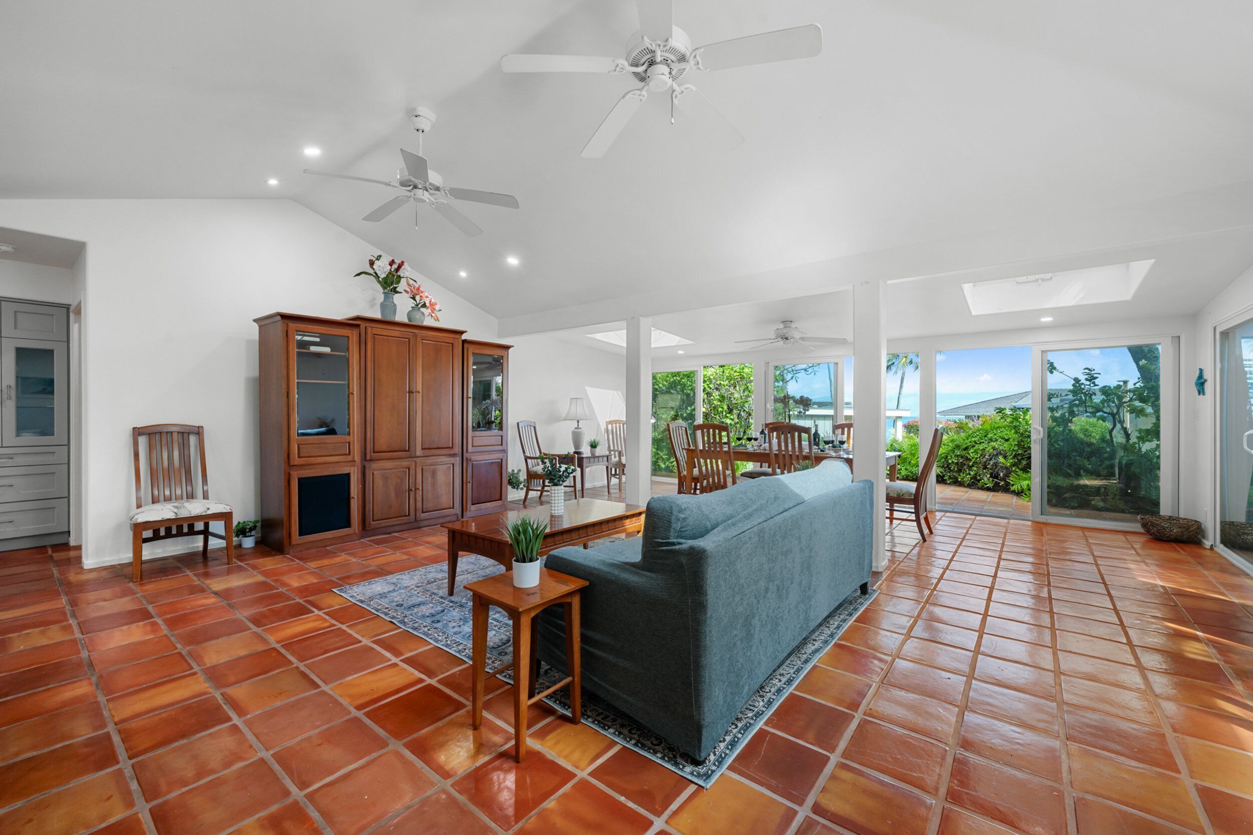 A spacious living area with a sofa, wooden cabinets, and a dining table.