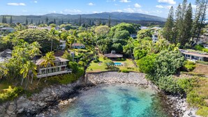 Une propriété située sur la côte, offrant une vue dégagée sur l’océan, une piscine et une végétation luxuriante.