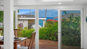 Une terrasse avec une table et des chaises, une vue sur la mer et un jardin avec différentes espèces de plantes.