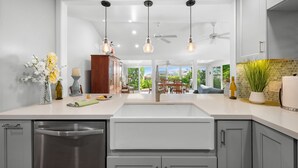 Une cuisine moderne dotée d’un îlot central, de luminaires suspendus et donnant sur un espace repas.