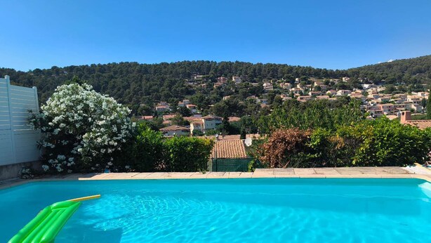 A clear blue swimming pool with a view of a hillside village. - Provence getaway just minutes from Cassis with private pool (Carnoux-en-Provence)