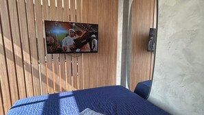 Een moderne hotelkamer met een groot bed, een flatscreen televisie bevestigd aan een houten lattenwand en een grote spiegel.