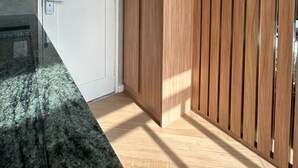 Een kamer met een witte deur, een houten garderobe en een granieten aanrechtblad.