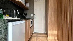 Een moderne keuken met een inbouwkoelkast, magnetron en spoelbak. Er is een houten kast en een deur met een raam.