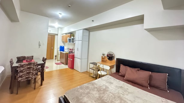 Une chambre moderne avec un lit, un canapé, un coin repas comprenant une table et des chaises, et une cuisine en arrière-plan.