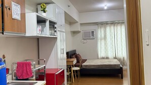 Une pièce de taille modeste comprenant un coin cuisine, un lit, un bureau et une chaise.