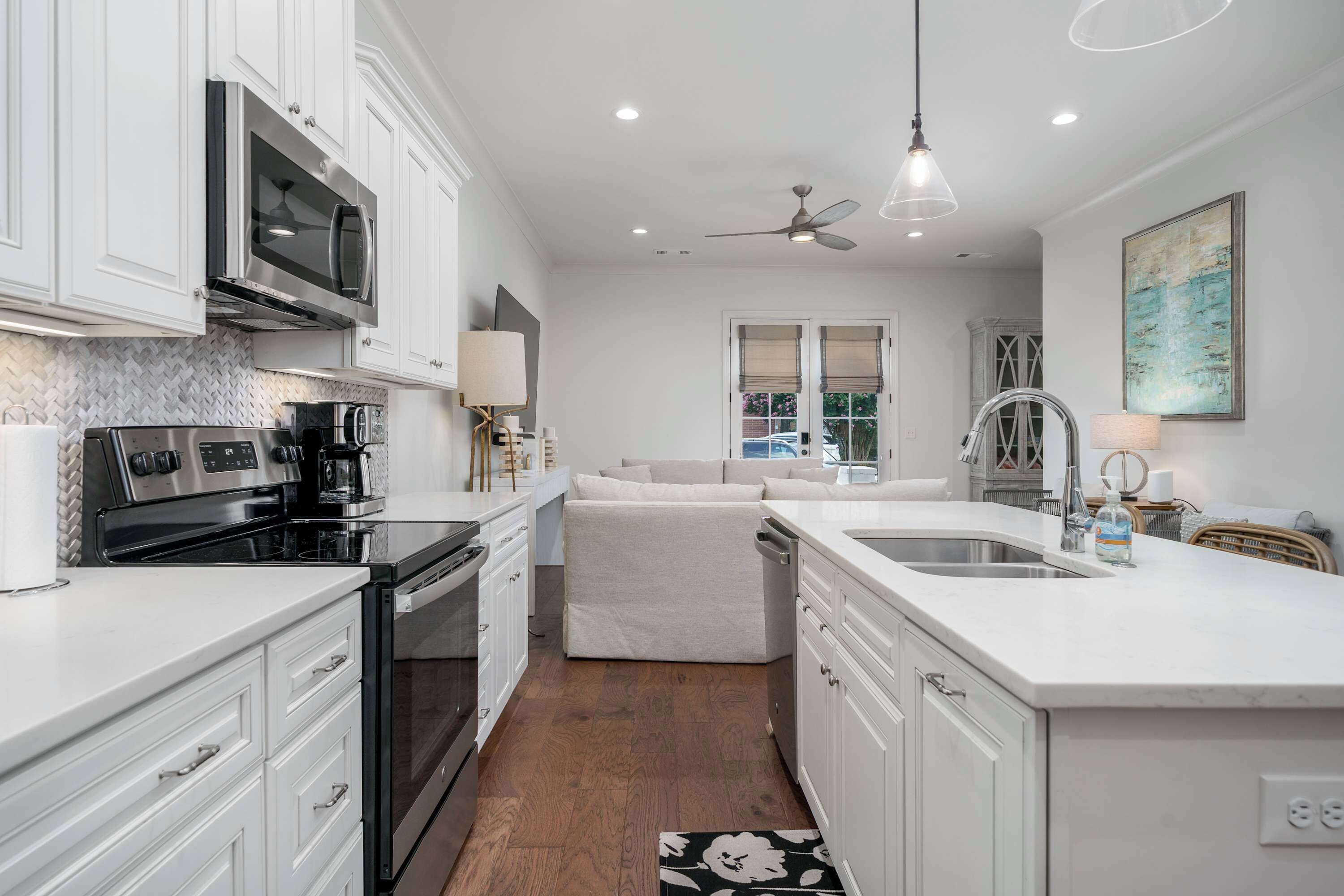 A modern kitchen with white cabinetry, stainless steel appliances, and a central island with a sink.