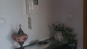 A room with a white console table, a decorative lamp, a potted plant, and a wall-mounted telephone.