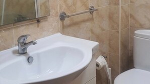 A bathroom with a white sink, a mirror, a toilet, and a shower.