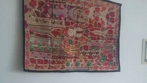A hotel room with a large bed, two bedside lamps, and a colorful tapestry on the wall.