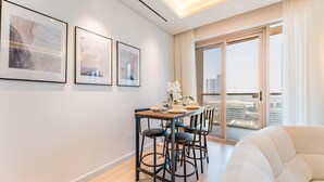 Ein modernes Wohnzimmer mit einer Couch, einem Esstisch mit Stühlen und einem großen Fenster mit Blick auf die Stadt.