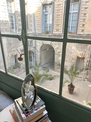 Blick durch ein Fenster, mit einem verzierten Metallgegenstand und Büchern auf einem Tisch.
