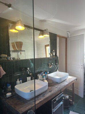 Ein Badezimmer mit zwei weißen Waschbecken, einem großen Spiegel und Pendelleuchten.