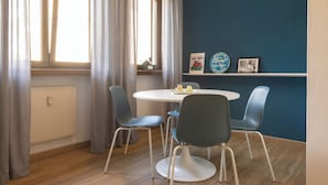 A dining area with a round table, four chairs, and a window with curtains.