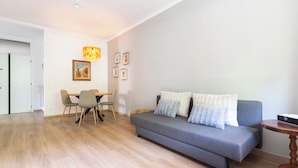 A modern living room with a grey sofa, wooden dining table, and chairs.