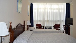 Una habitació d'hotel amb dos llits, una televisió, un escriptori i una cadira.