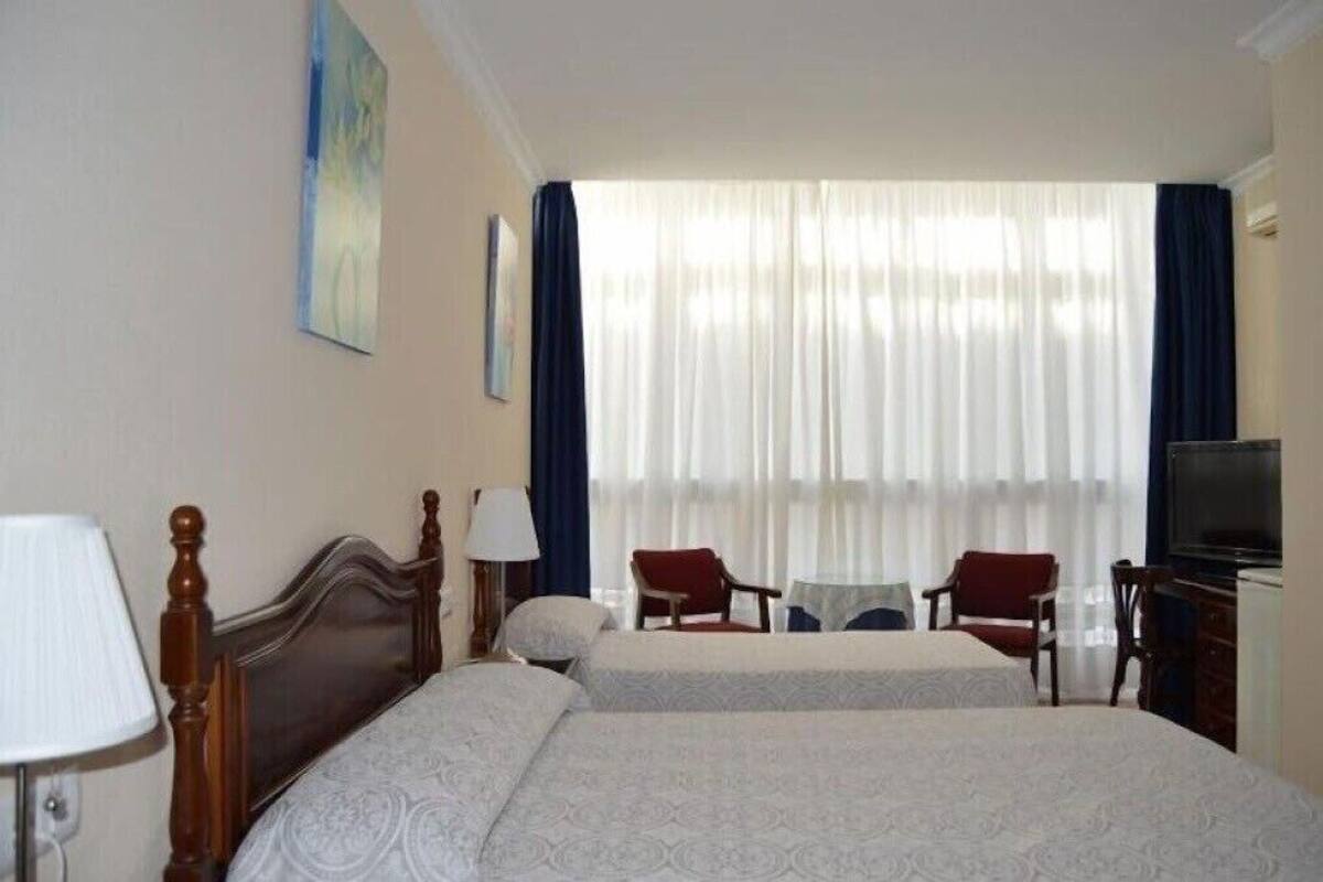 A hotel room with two beds, a television, a desk, and a chair.