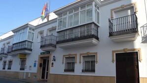 Un bâtiment blanc doté de nombreux balcons, d’une porte et d’un drapeau.