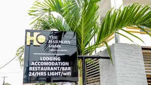 A sign for The Harmony Oasis Hotel & Suites advertising lodging, accommodation, restaurant/bar, 24/7 light, and wifi. - The Harmony Oasis Hotel and Suites (Port Harcourt)