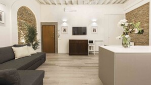 Un salon moderne avec un canapé, un téléviseur, un meuble en bois et une plante décorative.