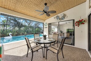Un patio techado con piscina, mobiliario exterior y ventilador de techo.
