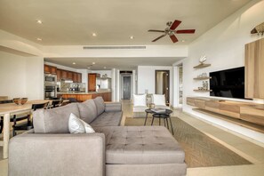 Ein modernes Wohnzimmer mit einem Ecksofa, einem Essbereich und einer Küche im Hintergrund.