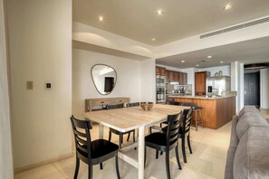 Een moderne keuken met een centraal eiland, een eethoek met een houten tafel en stoelen, en een zithoek met een bank.